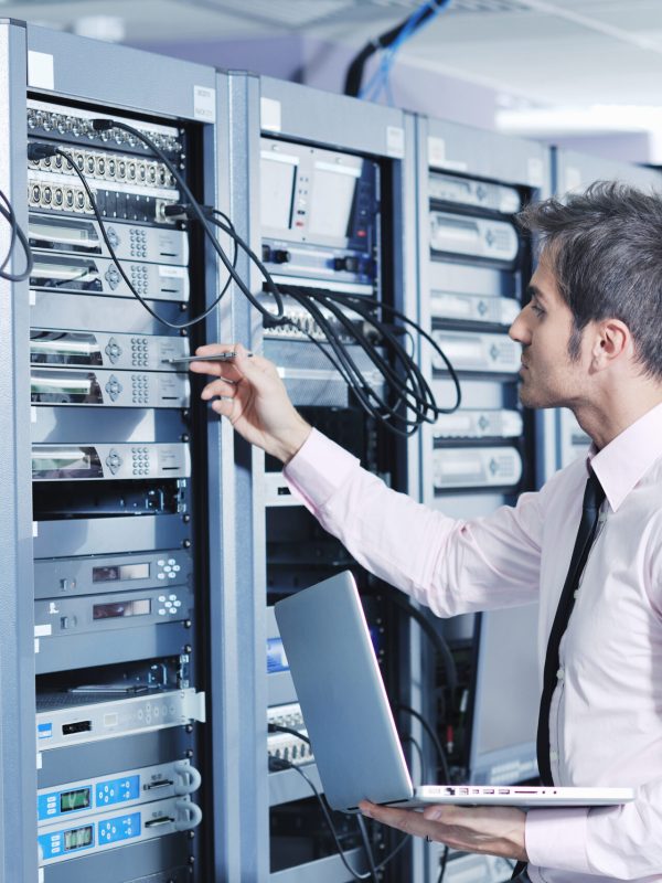 young engeneer business man with thin modern aluminium laptop in network server room
